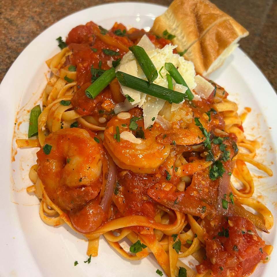 Shrimp linguine with red sauce, parmesan, green onions, and a side of bread.