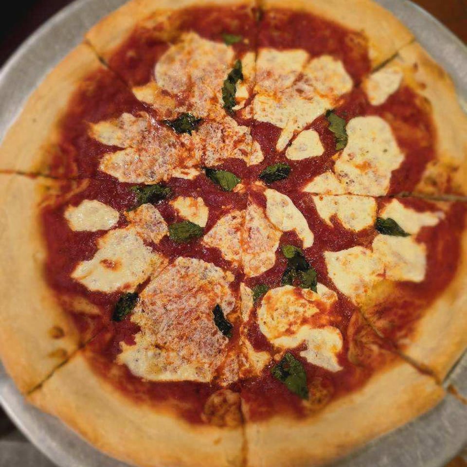 A whole Simo's Pizza Margherita, sliced, with fresh mozzarella, tomato sauce, and basil.